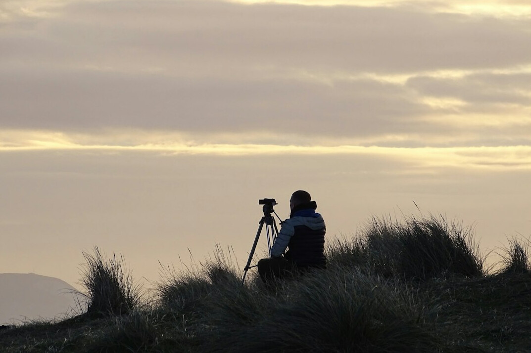 Field camera operator filming outdoors with a professional camera on a tripod